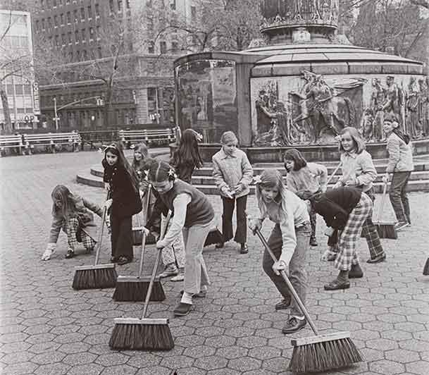 Black and white photo of a group of girls sweeping sidewalks in NYC on Earth Day.