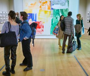 A group of visitors inside of a gallery with colorful works on the walls