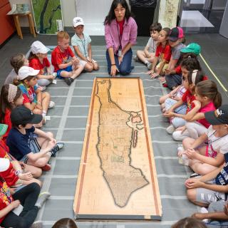A image of students and an educator looking at a map of Manhattan
