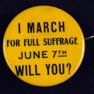 A small gold button supporting voting rights for women from the early 20th century reads: I March for Full Suffrage June 7th. Will You? 