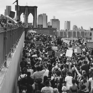 Black and white photo of protestors walking across the Brooklyn Bridge