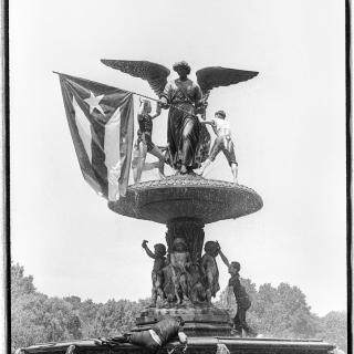 A fountain with a statue holding the Puerto Rican flag