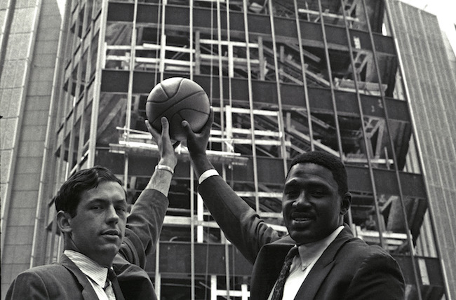 Bill Bradley and Willis Reed hold a basketball in the air out side the construction site for Madison Square Garden.