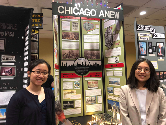 Two students stand on either side of their History Day project, an exhibit board that focused on “The Tragedy of the Great Fire and the Triumph of Skyscraper City” 