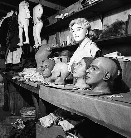 Wax heads and bodies sit on a workbench and are suspended from the ceiling of Hattie McKeever’s workshop