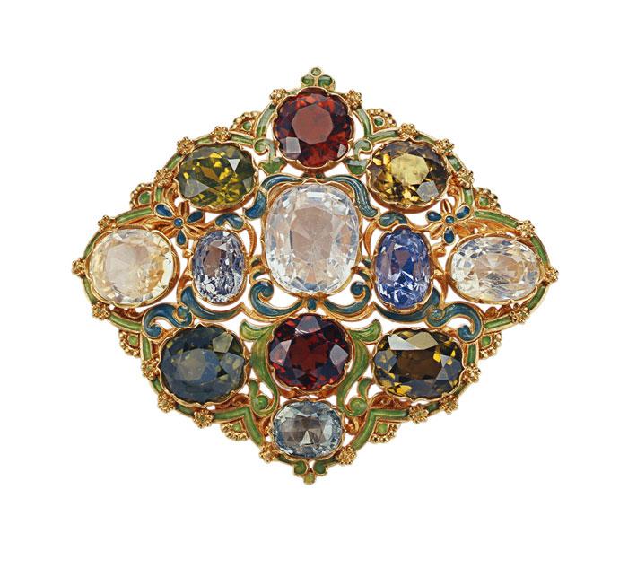 Brooch made of metal, painted green and teal with gold pieces and edges. A number of large gemstones are set in the metal