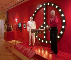 Mannequins wearing festive clothing in front of a peace sign