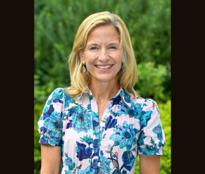 An image of a white woman in a floral shirt set against trees in the background