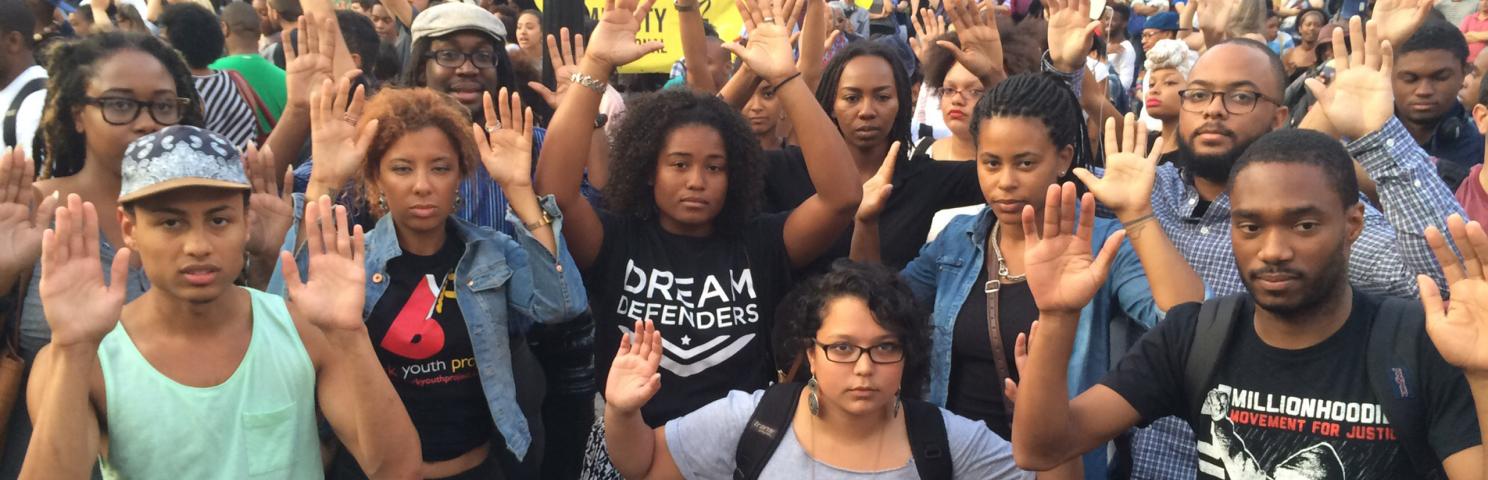 Black Lives Matter protesters with their hands in the air in a sign of surrender and the “hands up don’t shoot” slogan