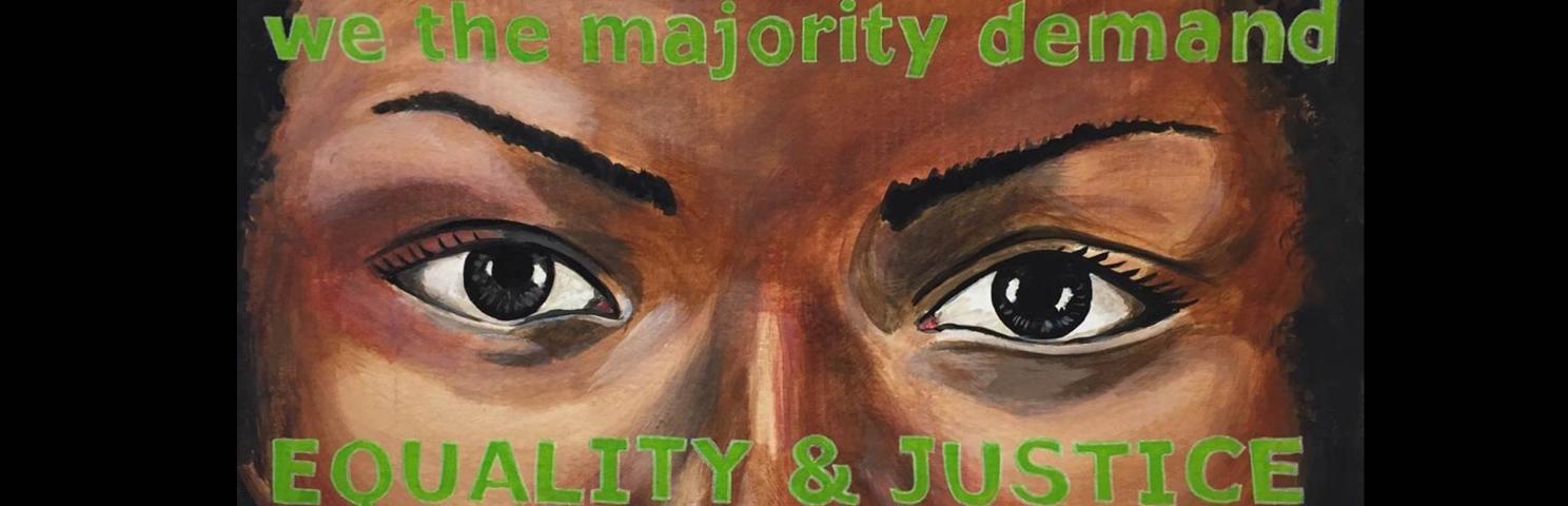 Painting of a woman’s eyes. Painted over her forehead and cheeks are the words “we the majority demand/EQUALITY & JUSTICE” 