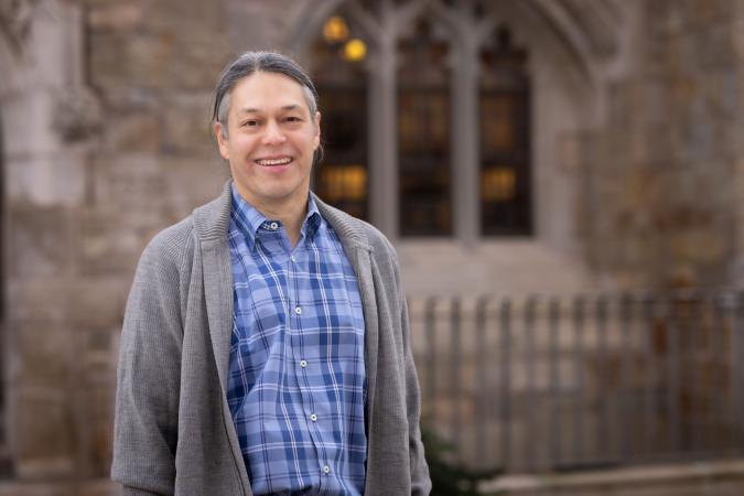 A portrait of Dr. New Blackhawk weather a gray cardigan and a blue patterned shirt.