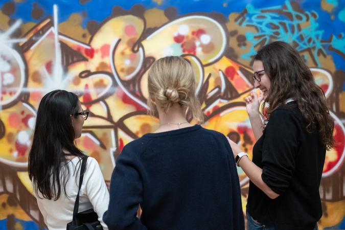 Three people standing in front of a painting