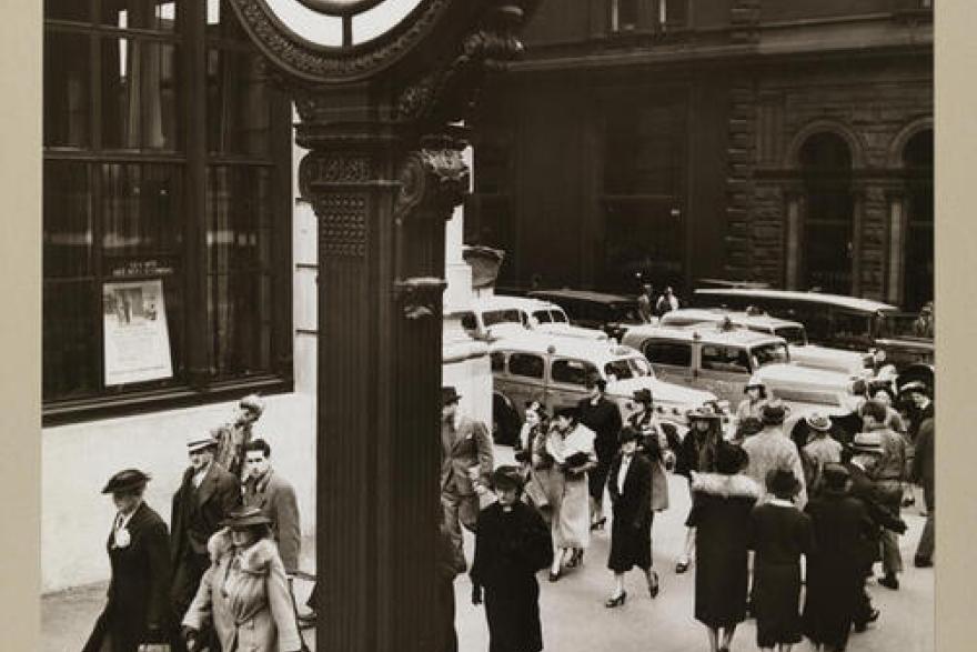 People walk past a clock tower. 