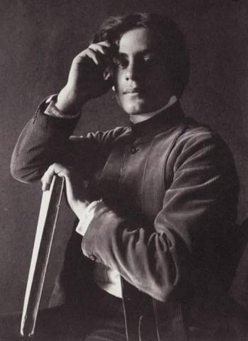 A man poses for the camera while leaning his elbow on a book.