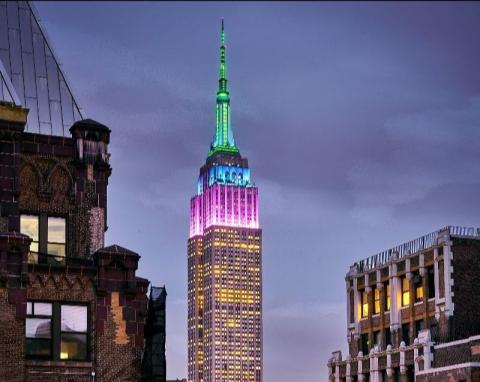 Photo of Empire State Building light in purple, blue, and green in honor of the Museum's Centennial