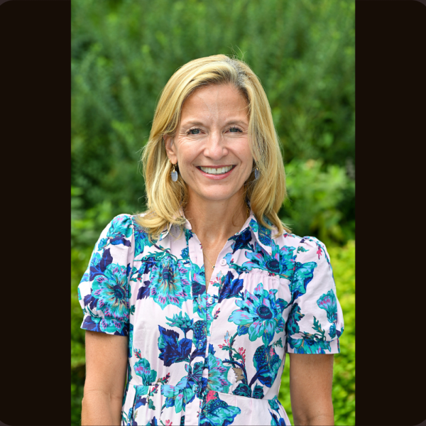 An image of a white woman in a floral shirt set against trees in the background