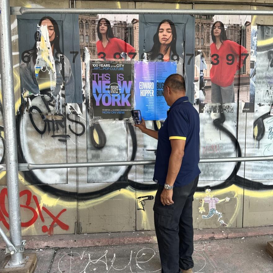 Man stops to use QR code on wild postings for the exhibition "This Is New York"