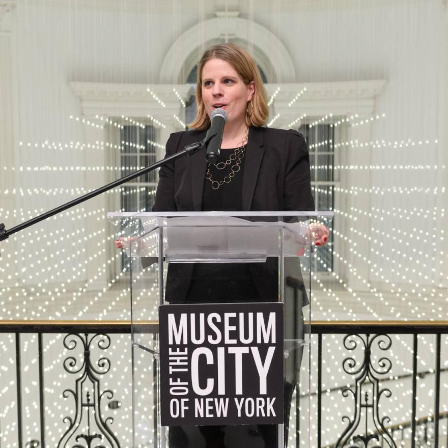 Image of curator Lilly Tuttle at clear podium with text logo "Museum of the City of New York"