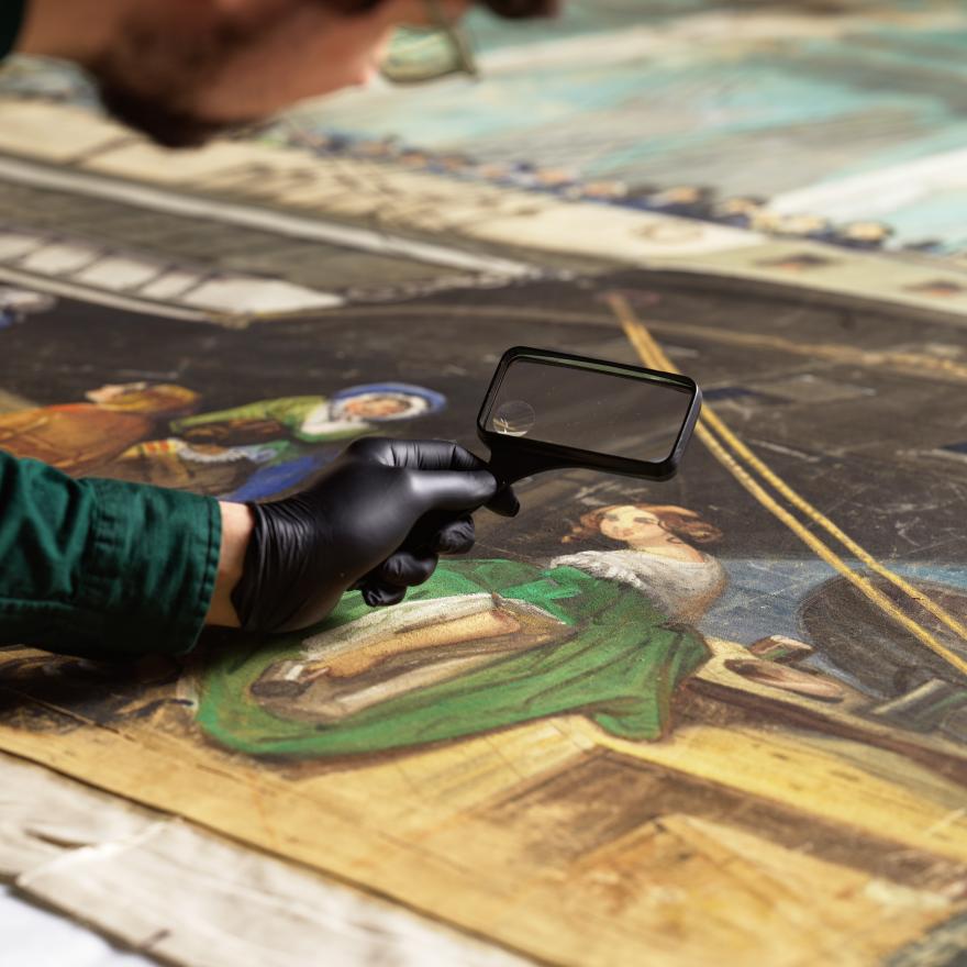 A man holds a magnifying glass over a painting of a woman in a green dress next to a ship.