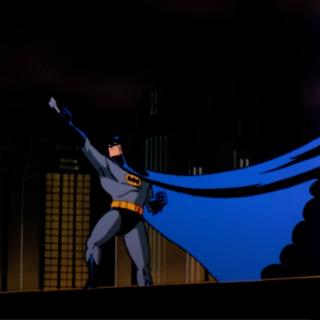 animated Batman standing on a rooftop with a dark city skyline in the background. He is holding a Batarang, ready to throw, and his blue cape billows dramatically. Iconic buildings, including one resembling the Chrysler Building, are visible.