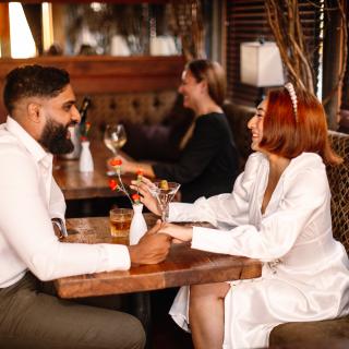 image of couple sitting at a table laughing and holding hands 